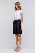 Woman wearing a white t-shirt and black skirt on a plain background