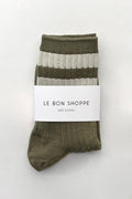 A pair of ribbed crew socks in olive green and light gray stripes, wrapped with a white paper band that reads 'LE BON SHOPPE HER SOCKS' on a clean white background.