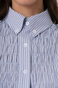 Close-up of a smocked button-down shirt with vertical blue and white stripes, featuring a pointed collar and white buttons.
