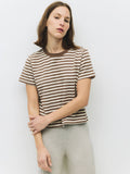 Woman wearing a striped shirt and light pants against a plain background