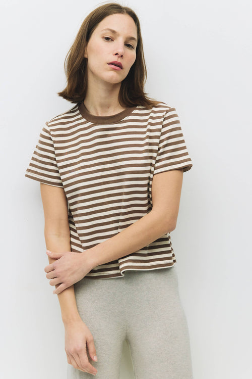 Woman wearing a striped shirt and light pants against a plain background