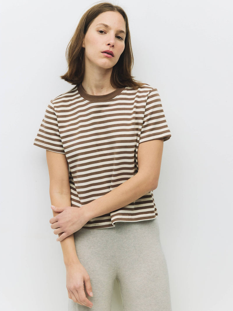 Woman wearing a striped shirt and light pants against a plain background