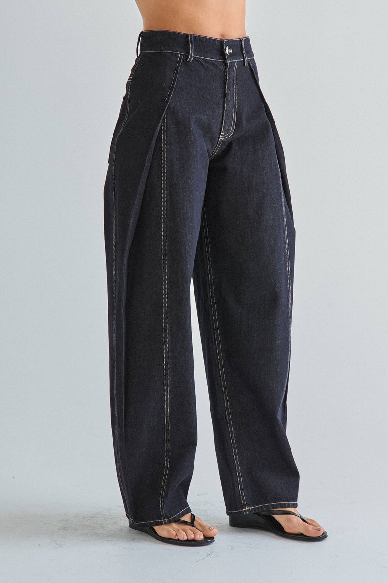 Person wearing dark blue wide-leg jeans on a light gray background