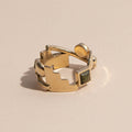A brass ring with gold tones, featuring a series of unakite stones in various shapes including circle and square, set within metallic frames.