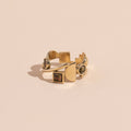A brass ring with gold tones, featuring a series of unakite stones in various shapes including circle and square, set within metallic frames.