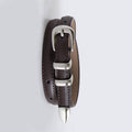 Brown leather belt with silver buckle and spike on a light gray background