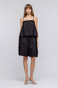Woman wearing a black ruffled dress on a gray background