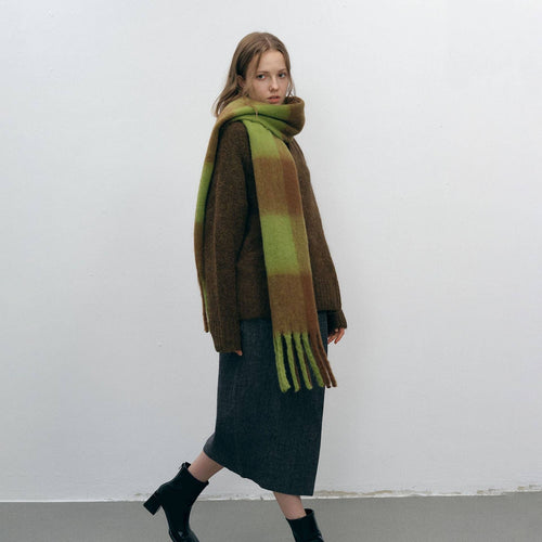Woman wearing a brown and green scarf against a white background