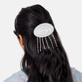 Person wearing a hair accessory with pearls and beads on a plain background