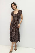 Woman wearing a brown dress with white polka dots against a white background