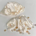 Decorative lace piece with pearls on a light gray background