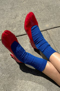 Red shoes with blue socks on a concrete surface