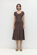 Woman wearing a brown polka dot dress against a white background