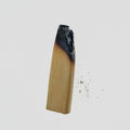 A single product isolated on a plain light gray background, with no person, animal, or real environment present, so subject_type is Product/Packaging. The object appears to be a tapered light wood or bamboo-like piece with a dark charred or burned section at the top and a few small dark specks to the right.