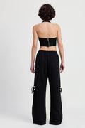 Person wearing a black strapless top and wide-leg pants on a white background