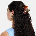 Woman with long, wavy hair wearing a decorative hair clip and earrings on a white background