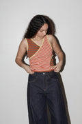 Person wearing a striped tank top and dark jeans against a plain background