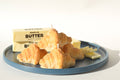 Croissants on a blue plate with a stick of butter on a white background