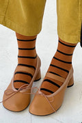 Person wearing striped socks with tan shoes on a light background