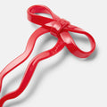 Red plastic tool shaped like a bow on a white background