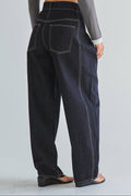 Person wearing dark blue jeans on a plain background