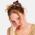 Woman with curly hair and floral headband against a white background