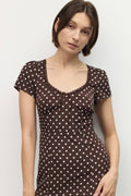 Woman wearing a brown polka dot dress against a white background