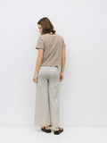 Woman wearing a striped shirt and light-colored pants on a white background
