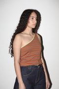 Woman wearing a striped tank top and dark jeans against a plain background