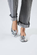 Silver shoes worn with rolled-up gray jeans on a white background