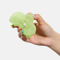 Hand holding a light green flower-shaped object with a pearl on a white background