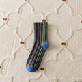 Striped sock with blue toes on a textured beige surface