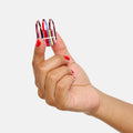 Hand holding a small container of colorful nail polish with a white background