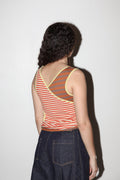 Person wearing a striped tank top and dark pants against a white background