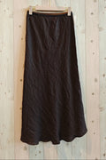 Black skirt hanging on a wooden hanger against a light wooden panel background