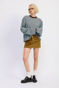 Person wearing a striped sweater and corduroy skirt on a white background