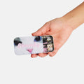Hand holding a small tin with a cat face design and hair clips inside, on a white background.