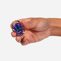 A hand holding a realistic jewel beetle insect toy against a plain light gray background.
