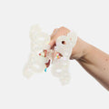 Hand holding a white lace-like hair clip against a light gray background