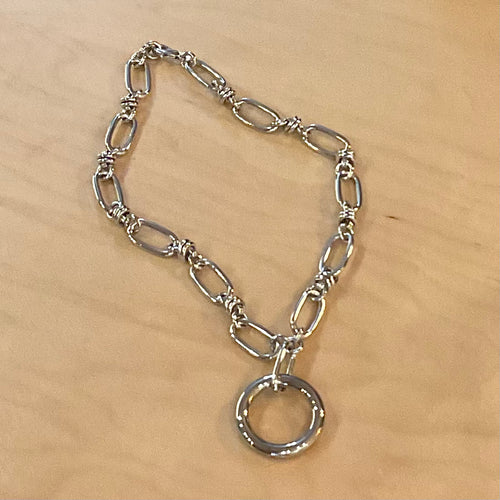 Silver chain necklace with a circular pendant on a beige background