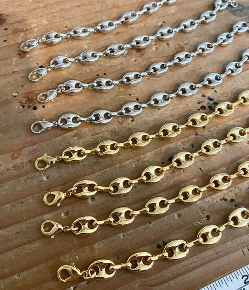 Three gold chains of different lengths on a wooden surface with a ruler for scale.