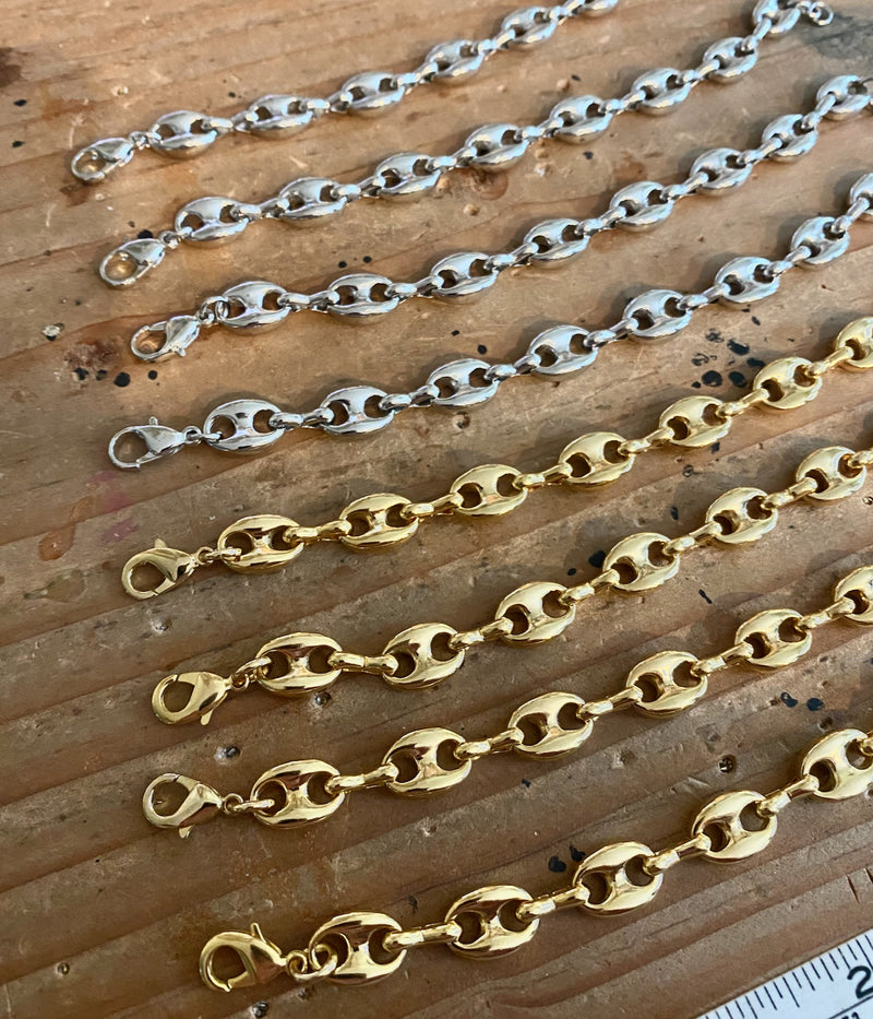 Three gold chains of different lengths on a wooden surface with a ruler for scale.
