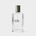 A clear glass perfume bottle with a reflective silver cap and a silver oval 'BLOMB' logo on the front, set against a plain light gray background.
