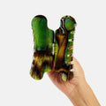 Hand holding a green and brown butterfly-shaped object against a white background