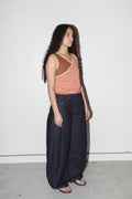 Woman wearing a striped tank top and dark pants against a white background