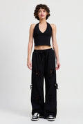 Woman wearing a black sports bra and wide-leg pants on a white background