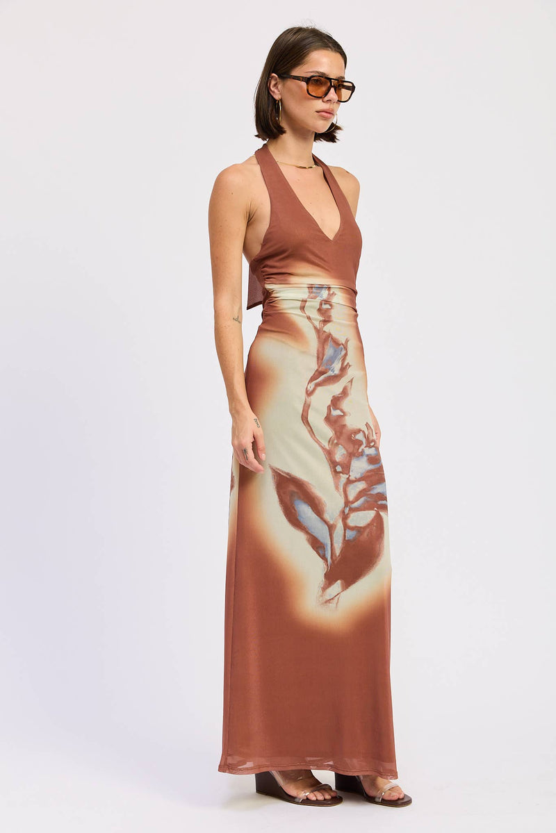 Woman wearing a brown halter top and long skirt with abstract pattern on a white background