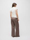 Woman wearing a white top and brown checkered pants on a plain background