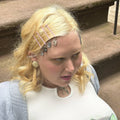 Person with blonde hair and decorative hairpins sitting on steps.