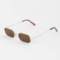 Sunglasses with gold frame and brown lenses on a light gray background